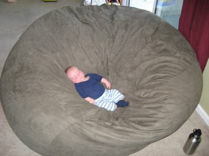 A picture of a young baby sleeping in the center of a giant Fombag