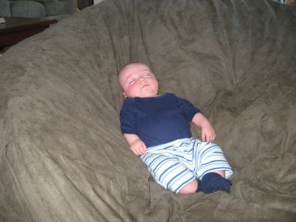 A closer picture of a young baby sleeping in the center of a giant Fombag
