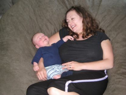 A close up of a mother and young son smiling at each other while resting in a giant Fombag
