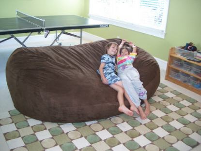A couple of small children sitting on the side of a giant, brown Fombag