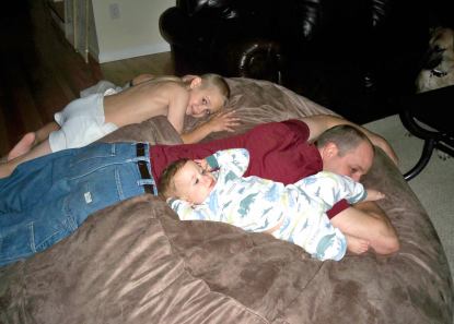 A father lying face down on a giant Fombag with his two young children