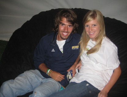 A picture of a young man and woman sitting comfortably on a brown, giant Fombag
